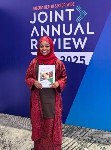 Zaiyanatu Abubakar Umar, N-CAS Focal Point, Federal Ministry of Health and Social Welfare at the Joint Annual Review in November 2025 holds a printed copy of the N-CAS following its launch. Photo Credit: Kris Saarlas.